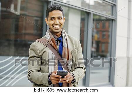 Stock Photography - Indian man using cell phone in city. Fotosearch
