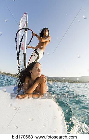 Stock Photo - Low angle view of couple windsurfing on ocean. Fotosearch
