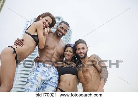 Stock Image - Low angle view of friends hugging on urban beach. Fotosearch