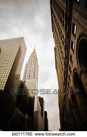 Stock Image - Low angle view of high rise buildings under cloudy sky, New York City, New York, United States. Fotosearch