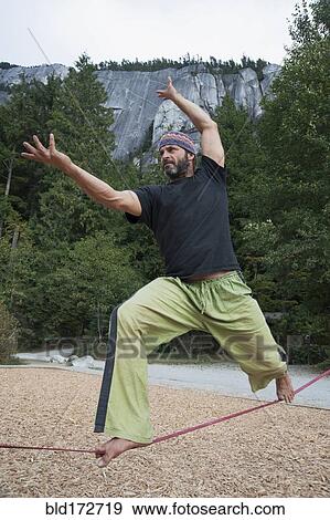 Stock Photo - Man balancing on slack line in park. Fotosearch
