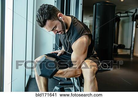 Stock Image - Man lifting weights in gymnasium. Fotosearch