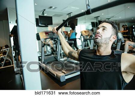 Man using exercise machine in gymnasium View Large Photo Image Stock Image - Man using exercise machine in gymnasium. Fotosearch