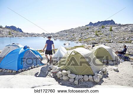 Man walking by tents at campsite in desert landscape View Large Photo Image Stock Image - Man walking by tents at campsite in desert landscape. Fotosearch