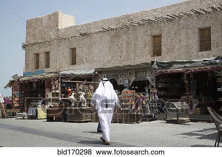Stock Photo - Man walking outside market on Doha sidewalk, Doha, Qatar. Fotosearch