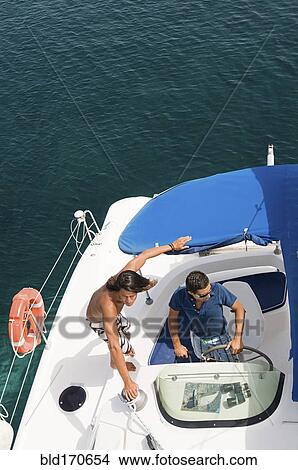Picture - Men driving sailboat on ocean. Fotosearch
