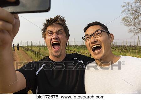 Stock Photography - Men taking selfie with cell phone in vineyard. Fotosearch
