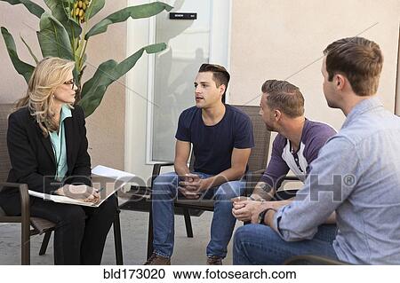 Stock Image - Men talking with therapist in group therapy. Fotosearch
