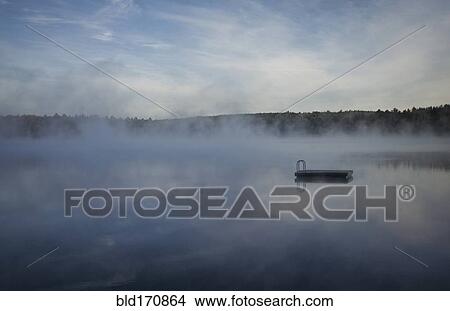 Picture - Mist clouds over still lake in remote landscape. Fotosearch