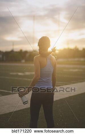 Mixed race athlete holding water bottle on sports field View Large Photo Image Stock Image - Mixed race athlete holding water bottle on sports field. Fotosearch