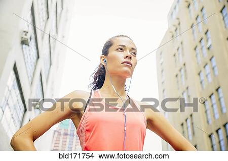 Picture - Mixed race athlete listening to earbuds in city. Fotosearch
