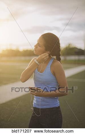 Stock Photo - Mixed race athlete listening to mp3 player on sports field. Fotosearch