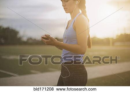 Stock Photo - Mixed race athlete listening to mp3 player on sports field. Fotosearch