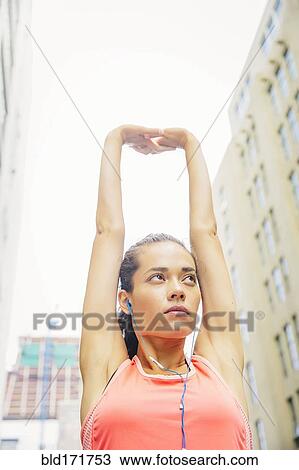 Stock Image - Mixed race athlete stretching in city. Fotosearch