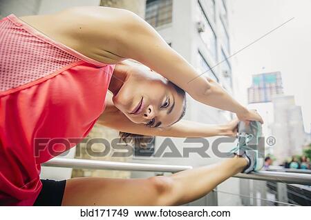 Stock Photo - Mixed race athlete stretching on banister. Fotosearch
