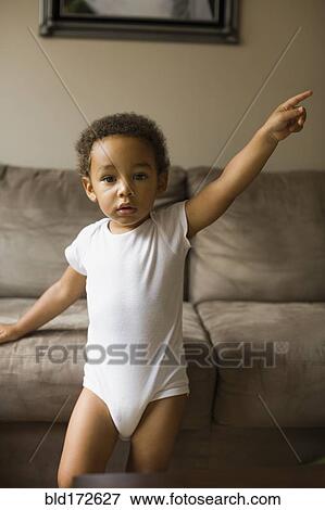 Stock Photo - Mixed race boy playing on sofa in living room. Fotosearch
