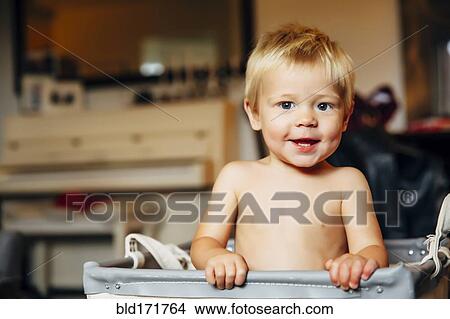 Picture - Mixed race boy sitting in laundry hamper. Fotosearch
