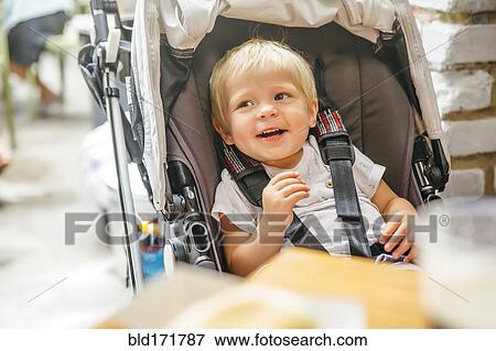 Stock Photo - Mixed race boy sitting in stroller chair. Fotosearch