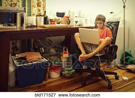 Stock Photo - Mixed race boy using laptop in living room. Fotosearch
