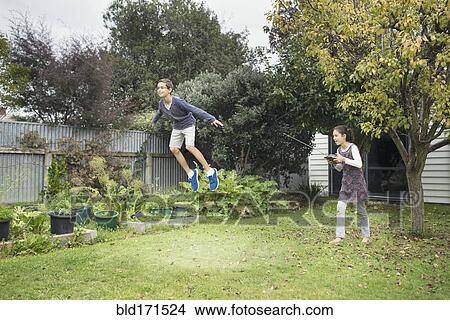 Mixed race children playing with hover toy in backyard View Large Photo Image Picture - Mixed race children playing with hover toy in backyard. Fotosearch