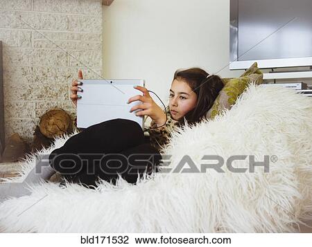 Mixed race girl using digital tablet in bean bag View Large Photo Image Stock Image - Mixed race girl using digital tablet in bean bag. Fotosearch