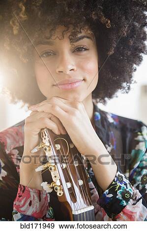 Stock Photo - Mixed race musician holding guitar. Fotosearch