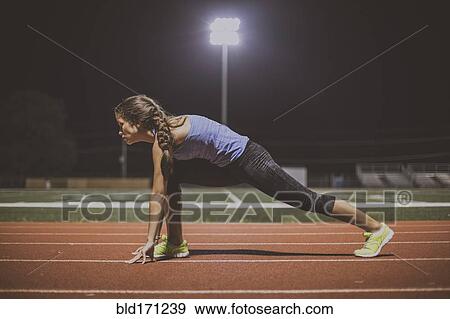 Stock Photo - Mixed race runner in starting position on sports field. Fotosearch