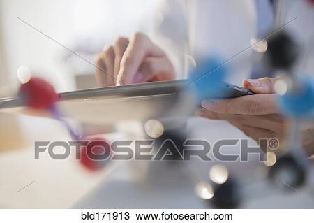 Stock Image - Mixed race scientist using digital tablet in laboratory. Fotosearch