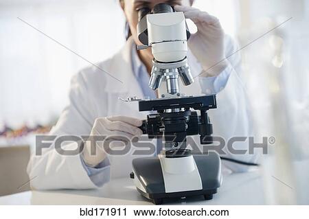 Stock Image - Mixed race scientist using microscope in laboratory. Fotosearch