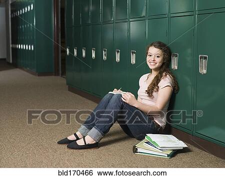 Stock Photograph - Mixed race student sitting at locker in school hallway. Fotosearch