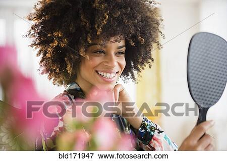 Mixed race woman admiring herself in mirror View Large Photo Image Stock Photo - Mixed race woman admiring herself in mirror. Fotosearch