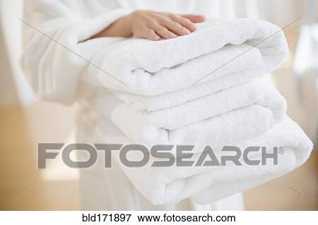 Stock Photo - Mixed race woman carrying stack of clean towels. Fotosearch