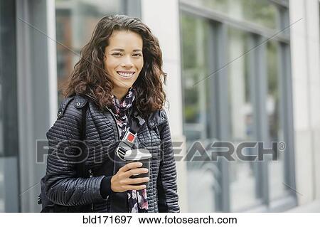 Stock Photo - Mixed race woman drinking coffee in city. Fotosearch