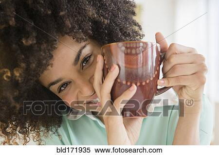 Stock Photography - Mixed race woman drinking cup of coffee. Fotosearch