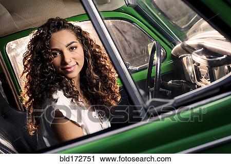 Stock Image - Mixed race woman driving vintage car. Fotosearch
