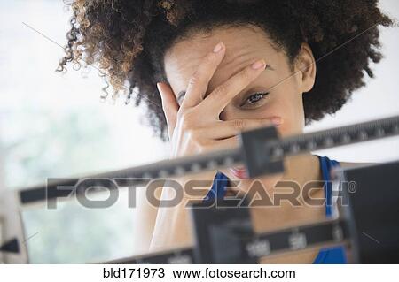 Mixed race woman hiding from weight on scale View Large Photo Image Stock Image - Mixed race woman hiding from weight on scale. Fotosearch