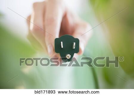 Stock Image - Mixed race woman holding electrical plug. Fotosearch