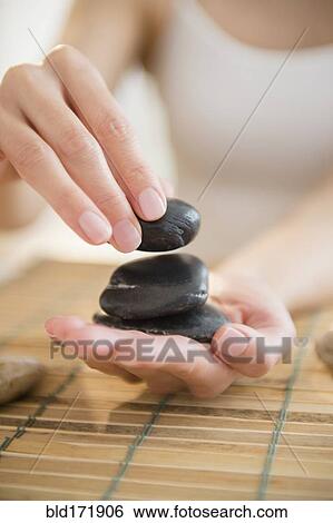 Stock Photograph - Mixed race woman holding massage stones . Fotosearch