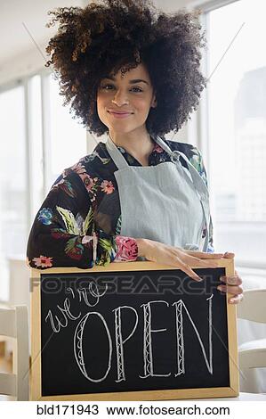Mixed race woman holding open sign in cafe View Large Photo Image Stock Image - Mixed race woman holding open sign in cafe. Fotosearch