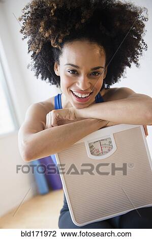 Mixed race woman holding scale View Large Photo Image Stock Image - Mixed race woman holding scale. Fotosearch