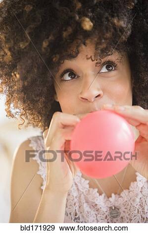 Mixed race woman inflating balloon View Large Photo Image Stock Photo - Mixed race woman inflating balloon. Fotosearch