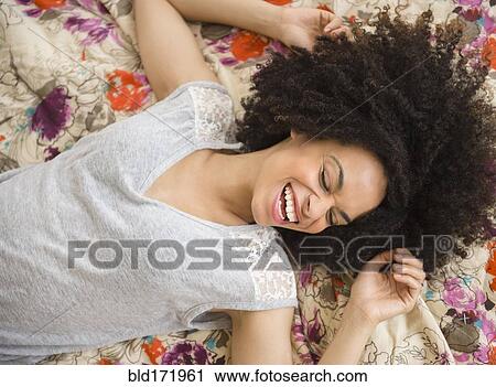 Stock Image - Mixed race woman laying on bed. Fotosearch