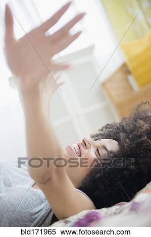 Stock Photography - Mixed race woman laying on bed. Fotosearch