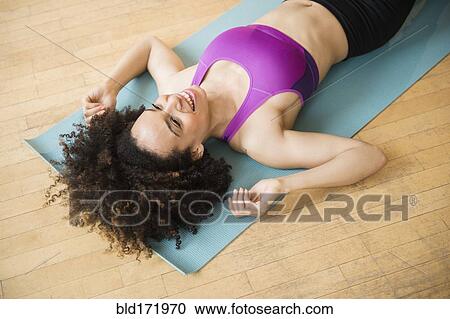 Mixed race woman laying on exercise mat on floor View Large Photo Image Stock Image - Mixed race woman laying on exercise mat on floor. Fotosearch