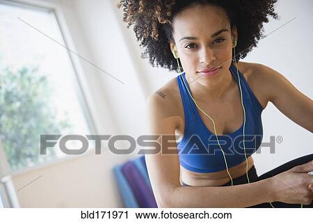 Stock Image - Mixed race woman listening to headphones. Fotosearch