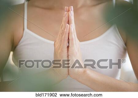 Stock Image - Mixed race woman meditating with clasped hands. Fotosearch