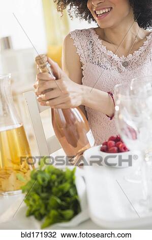Mixed race woman opening bottle of wine View Large Photo Image Stock Image - Mixed race woman opening bottle of wine. Fotosearch