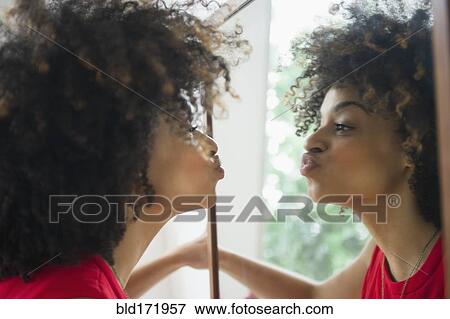 Stock Photo - Mixed race woman puckering in mirror. Fotosearch