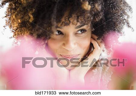 Stock Image - Mixed race woman resting chin in hands. Fotosearch