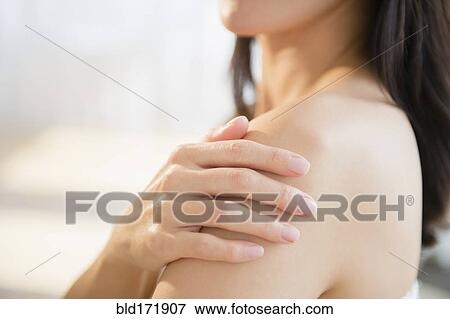 Mixed race woman rubbing lotion into skin View Large Photo Image Stock Photo - Mixed race woman rubbing lotion into skin. Fotosearch